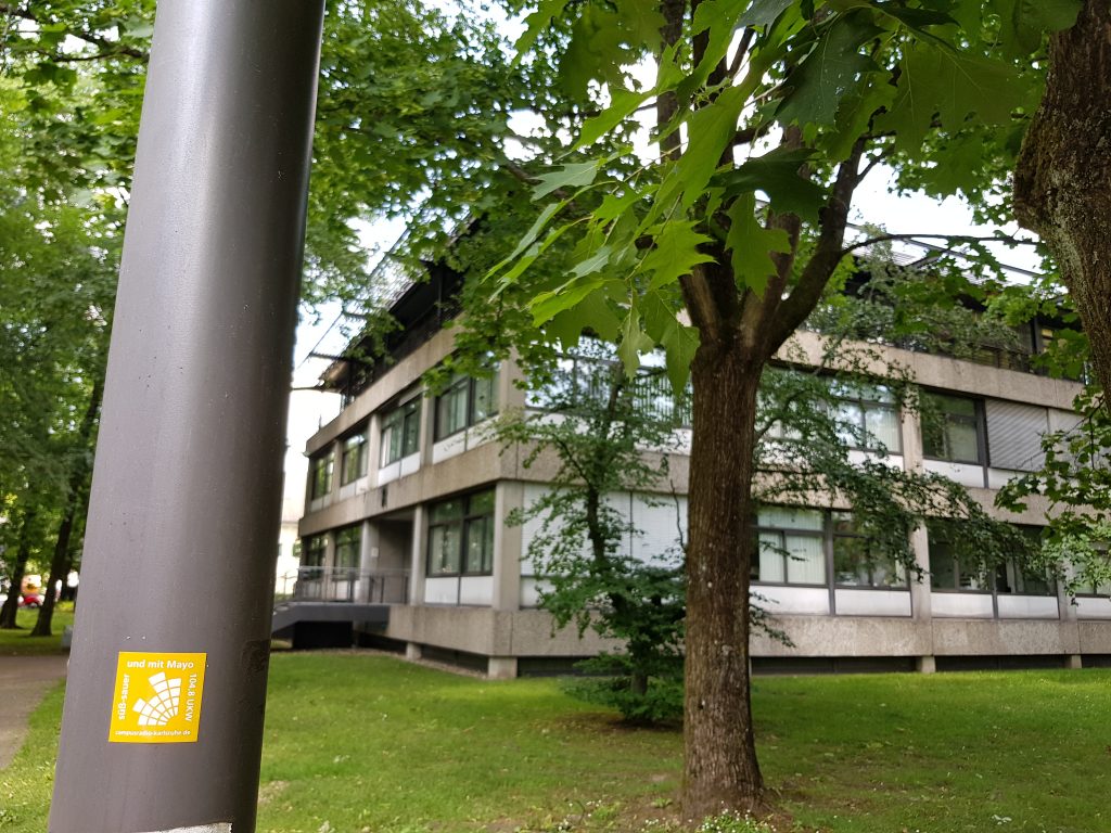 Laternenmast vor Hochschulgebäude mit Campusradio-Sticker