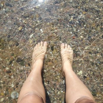 Ein paar Füße im klaren Flusswasser