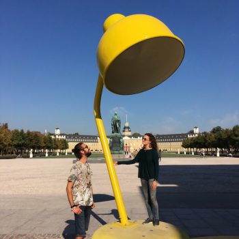 Josh und Francesca auf einer großen Schreibtischlampe als Kunstinstallation