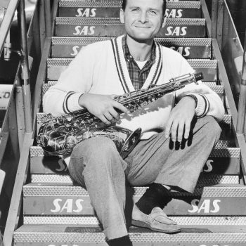 Mann sitzt auf einer Treppe und hält ein Saxophon