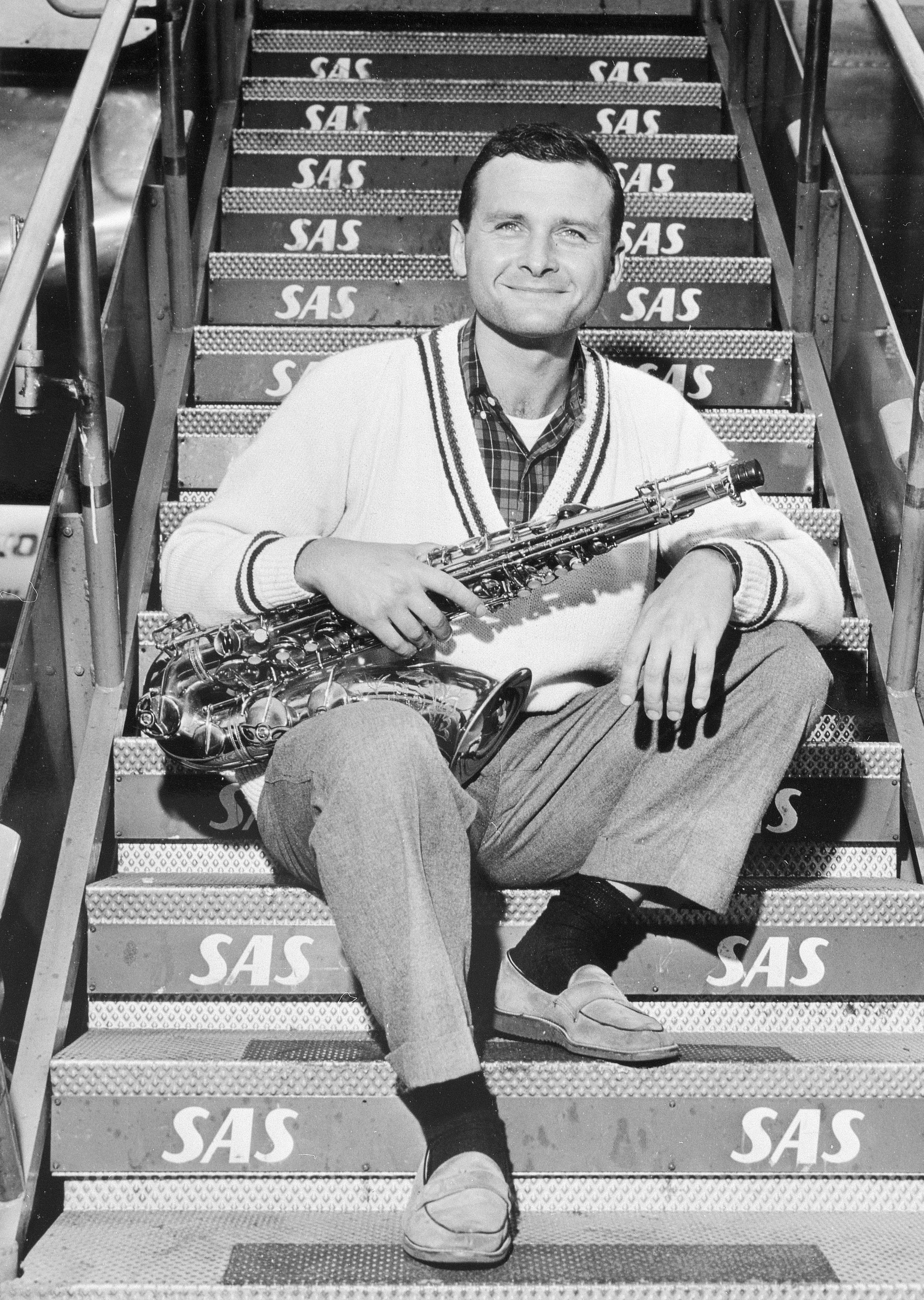 Mann sitzt auf einer Treppe und hält ein Saxophon