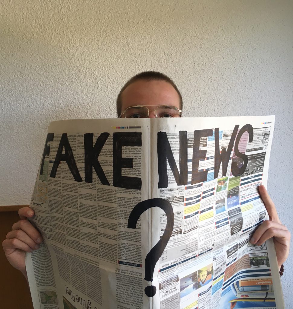 Mann hält Zeitung mit Aufschrift "Fake News?"