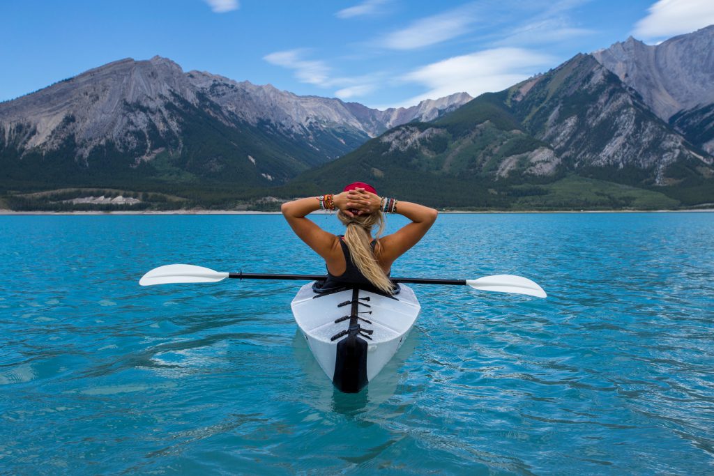 Frau im Kajak auf einem See mit Blick auf Berge
