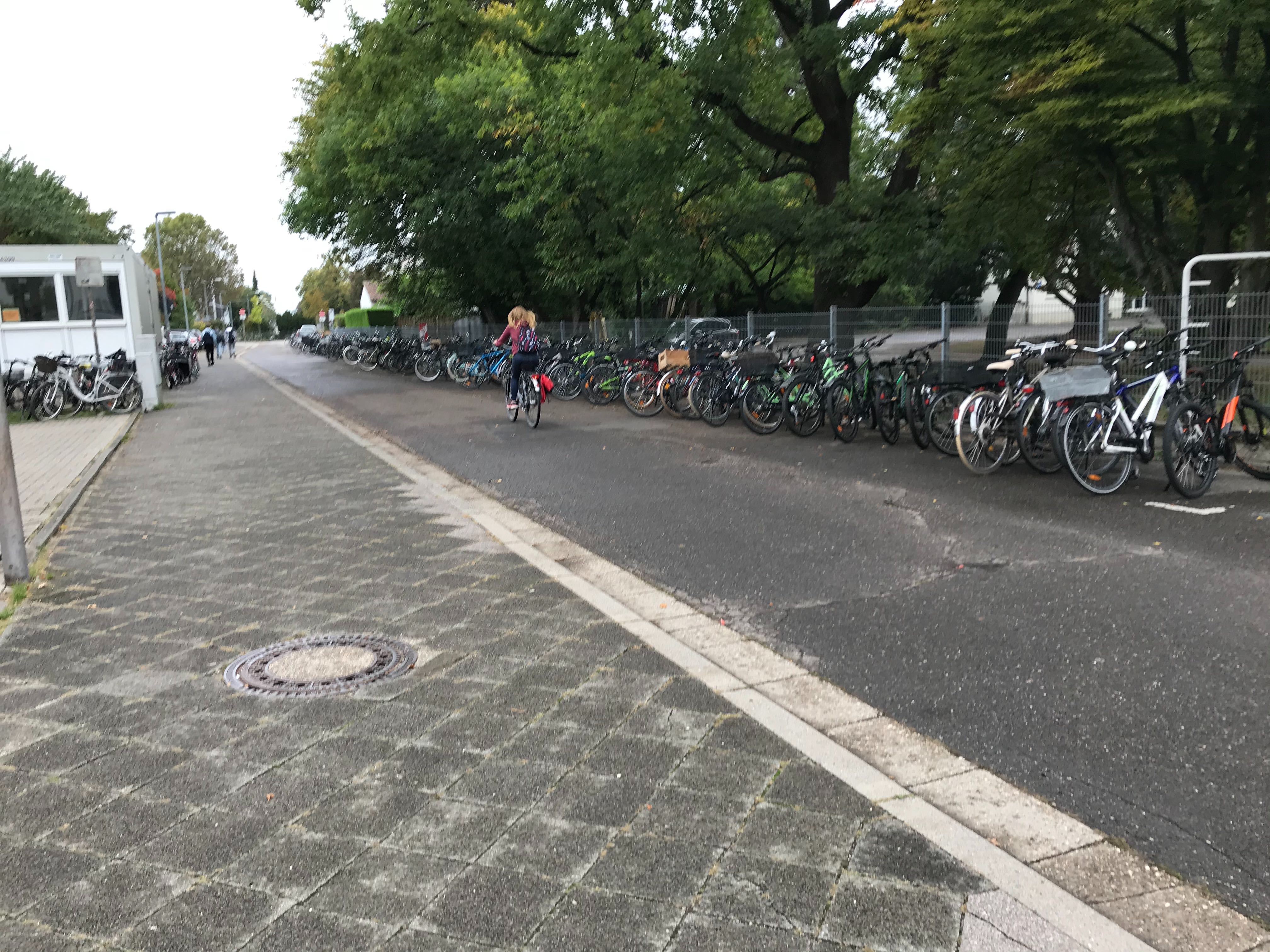 Straße, daneben ein Bürgersteig, auf dem viele Fahrräder geparkt sind