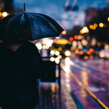 Schatten einer Person mit Regenschirm auf einer regennassen Straße