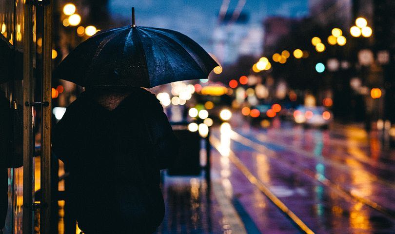 Schatten einer Person mit Regenschirm auf einer regennassen Straße