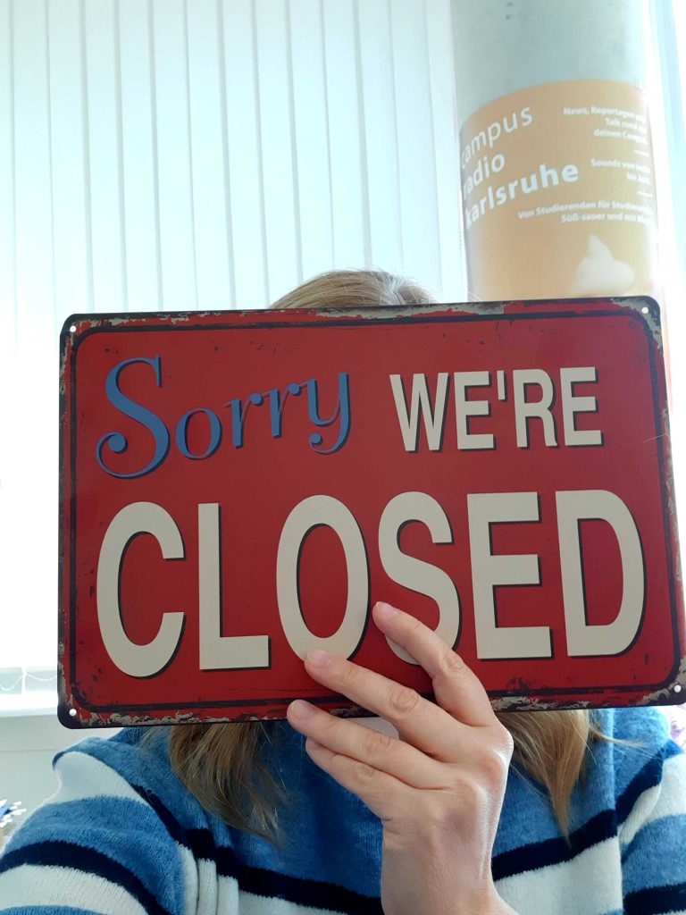 Frau hält Schild hoch "Sorry, we are closed"