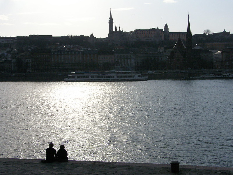 Zwei Menschen sitzen an einem Flussufer