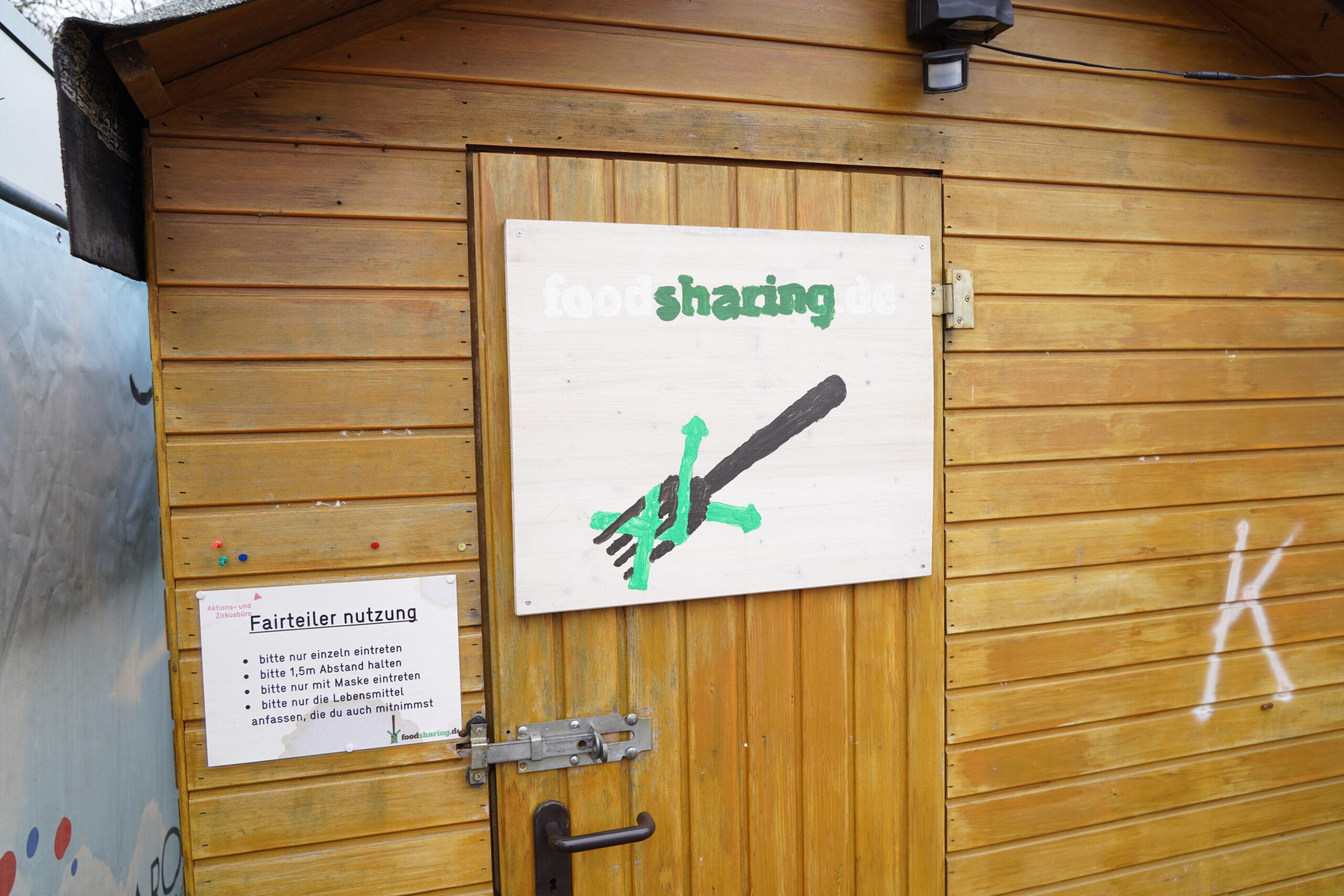 Holzhütte mit Schild "Fairteiler" an der Tür